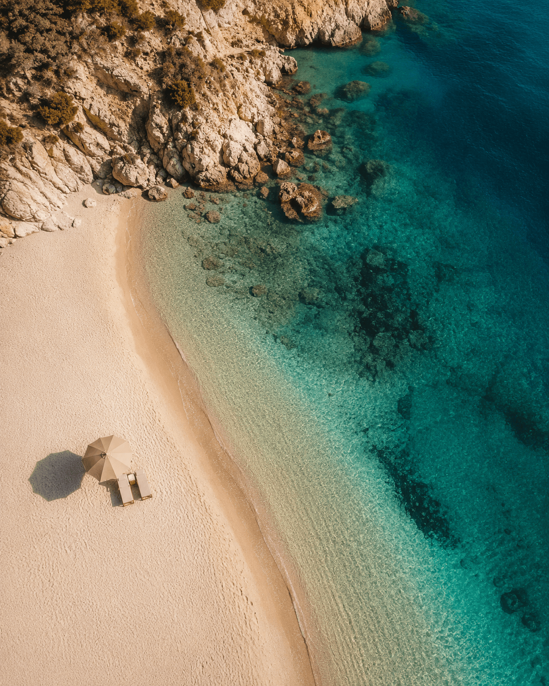A quiet cove with a single parasol on pale sand